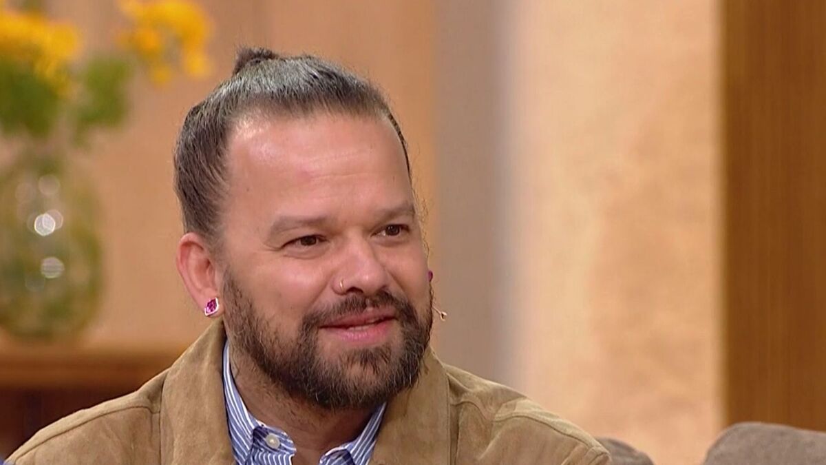 Michał Piróg występuje w programie „Pytanie na śniadanie” w zbliżeniu na twarz. Ma związane włosy, zarost oraz kolczyk w nosie i różowe kolczyki w uszach. Ubrany jest w jasnobrązową kurtkę i koszulę w paski, a na jego twarzy widać lekki uśmiech.