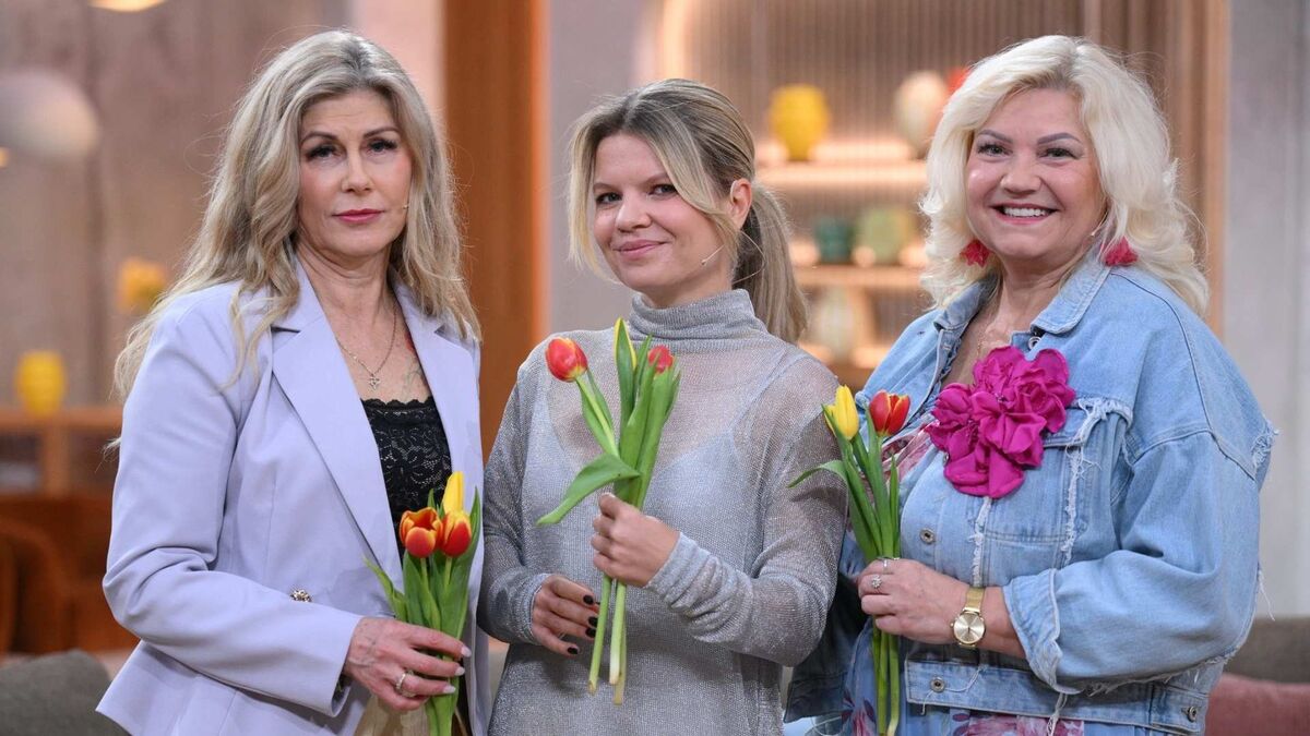 Ewa, Marta Manowska i Bożena stoją razem w studiu programu „Pytanie na śniadanie” i trzymają w dłoniach tulipany. Ewa ma jasną marynarkę i długie falowane włosy, Marta Manowska ma związane włosy i szary golf, a Bożena ma blond włosy, dżinsową kurtkę oraz dużą różową ozdobę przy sukience. Wszystkie stoją blisko siebie i uśmiechają się do zdjęcia.