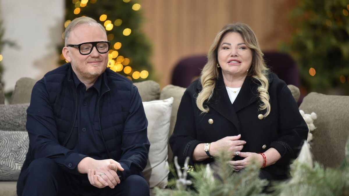 W studiu programu „Pytanie na śniadanie” Katarzyna Niezgoda i Paweł Markiewicz siedzą na jasnej kanapie na tle świątecznych dekoracji i lampek. Paweł Markiewicz ma ciemny strój i czarne okulary, a Katarzyna Niezgoda ma jasne, falowane włosy i czarną marynarkę ozdobioną złotymi guzikami. Na pierwszym planie widać rozmyte gałązki dekoracji, a w tle choinki z ciepłym oświetleniem.
